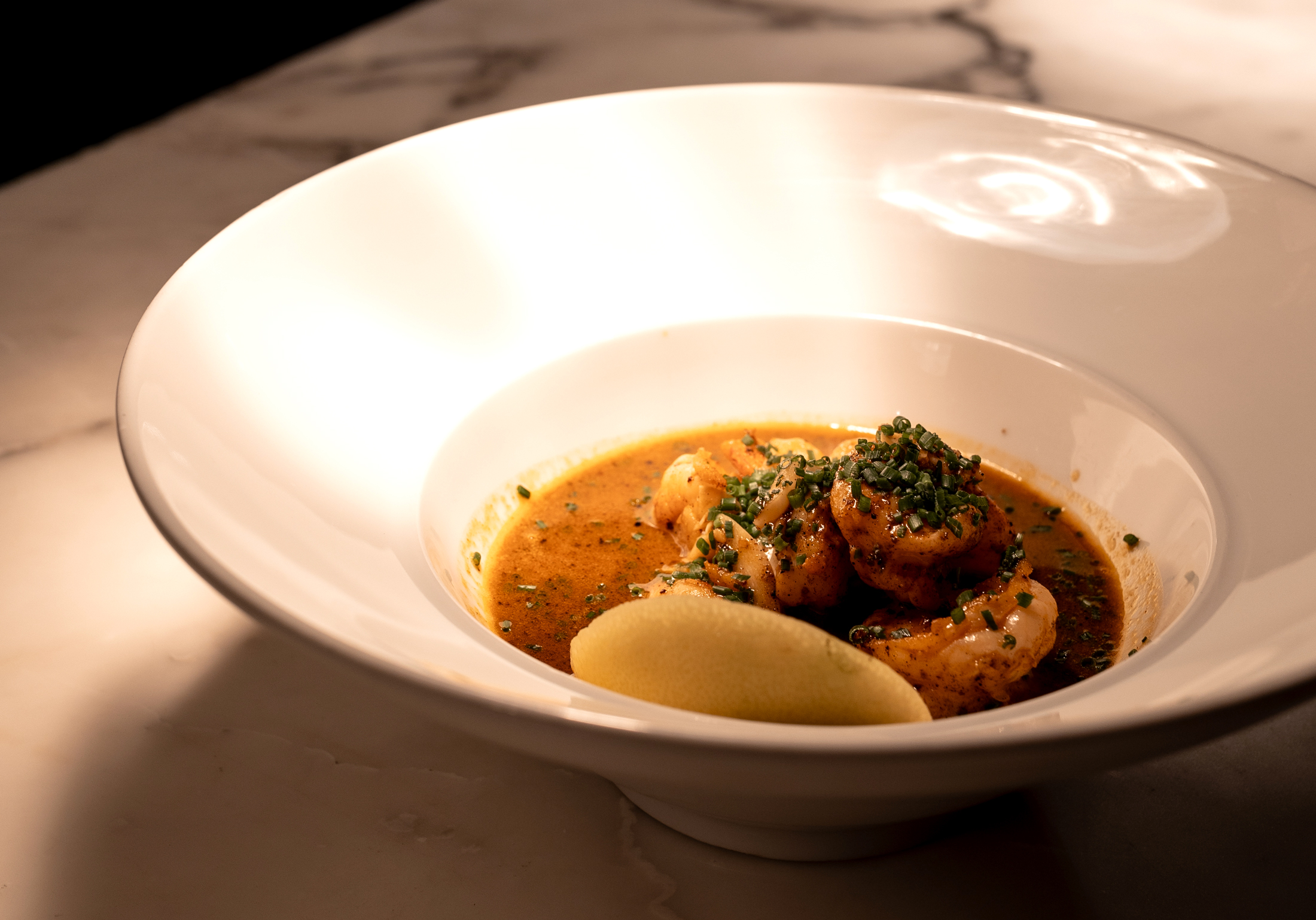 A close-up of a seasonal dish being plated at The Establishment's open kitchen